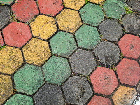 Textured red and green hexagonal stone pavers create a weathered pavement surface Abstract Background Concept Design