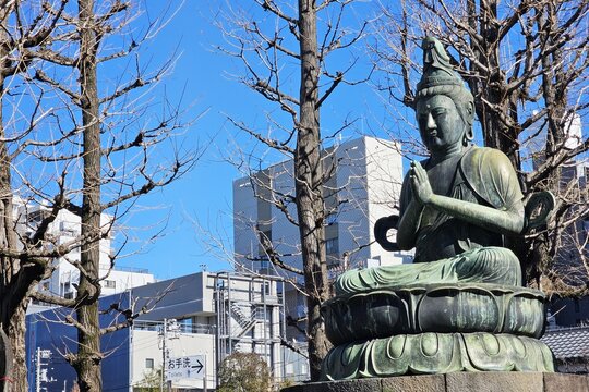 Bronze statue of Kannon Bodhisattva in a Japanese urban temple garden.