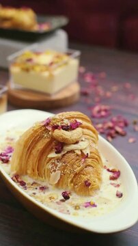 oum ali dish served in an oval bowl topped with an edible rose and cashew nuts