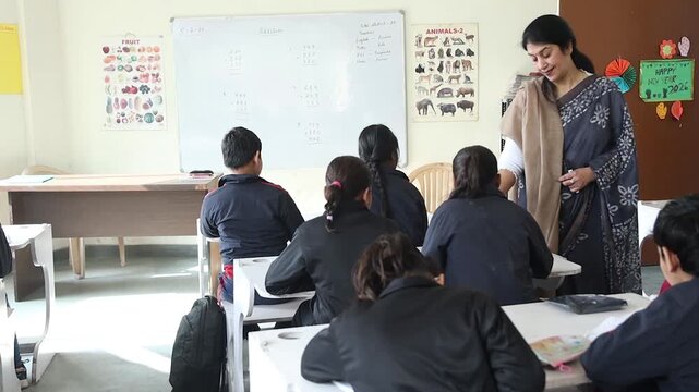 Indian female teacher teaching and helping students with studies in classroom , Examination, Education india.