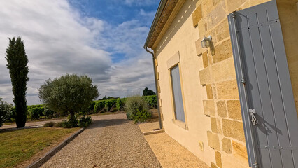 Obraz premium Stone Winery Building Overlooking Lush Green Vineyards in Bordeaux France