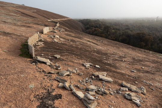 The ruin of a wall built above Wave Rock, or Katter Kich, Hyden, Western Australia, Australia. The wall was built on the granite dome to capture rainwater for the nearby town's water supply.
