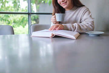 Obraz premium Closeup image of a woman reading a book and drinking coffee