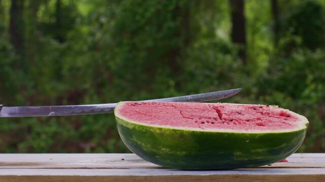Ninja fruit watermelon. Samurai sword cuts watermelon. Fresh summer juicy fruit on wooden table at nature. Katana katana slices watermelon. Watermelon fresh summer fruit.