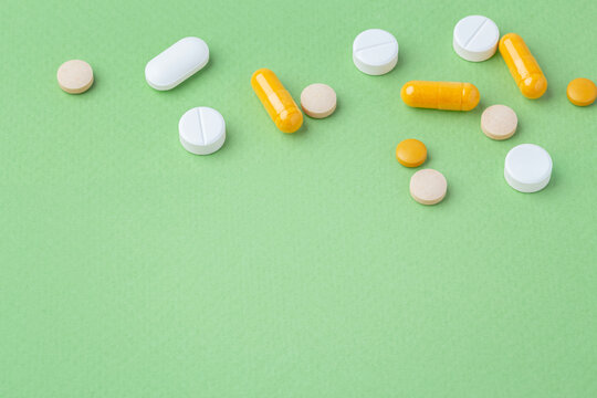 Capsule, pills and supplements on green background, copy space