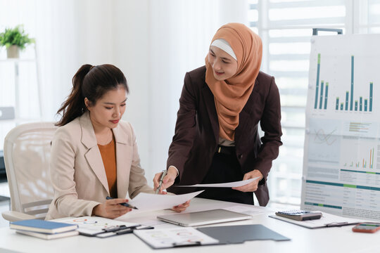 Two business colleagues multiethnic working in office, asian muslim