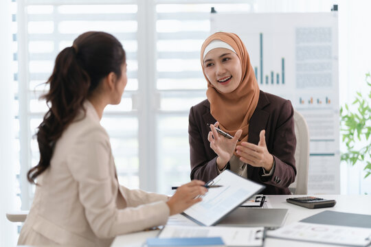 Two diverse colleagues discussing in conference room