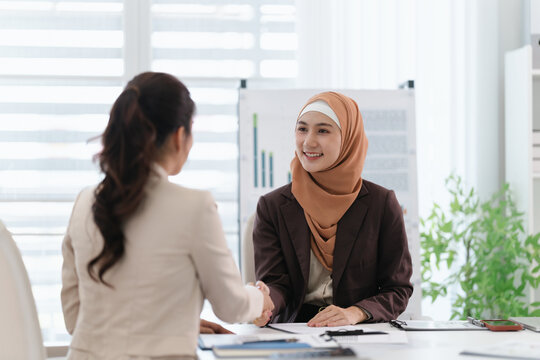 Two business colleagues multiethnic working in office, asian muslim