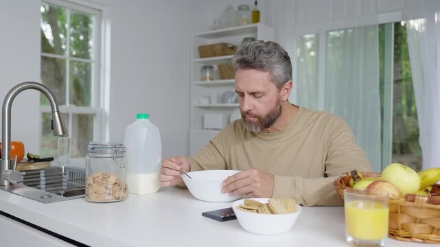 Kitchen scene of a man preparing healthy food in the morning. Morning kitchen lifestyle with a man focused on nutrition. Man in kitchen preparing a clean eating breakfast in the morning.