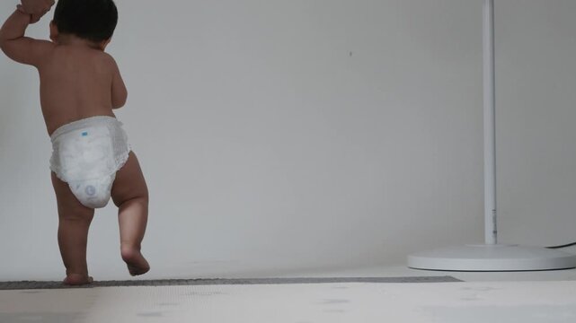 Close up of cute baby feet taking first steps on mat with parent support.