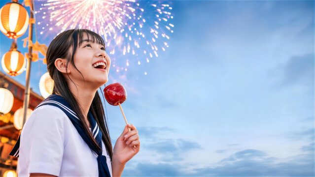 夏祭りでりんご飴を手に花火を見上げる女子学生