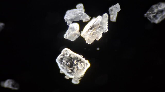 Microscopic view of table salt crystals with focus pull on black background, macro. 