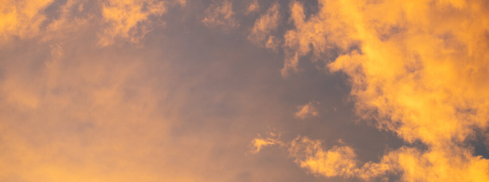 Beautiful dramatic sunset sky with vibrant orange and dark blue illuminated clouds