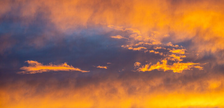 Beautiful dramatic sunset sky with vibrant orange and dark blue illuminated clouds