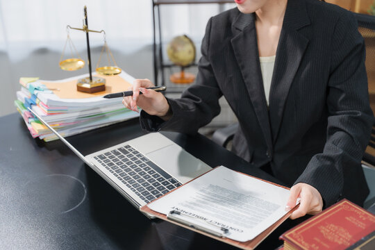 Legal Professional at Work: A dedicated legal professional, dressed in a formal suit, meticulously reviews documents and works on a laptop in a law office setting.