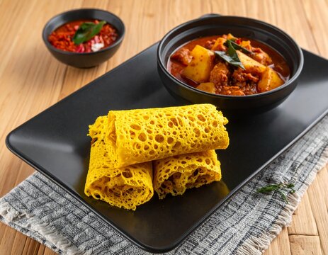 Traditional Roti Jala with spicy chicken curry and sambal, net pancake served on a black plate, Asian cuisine