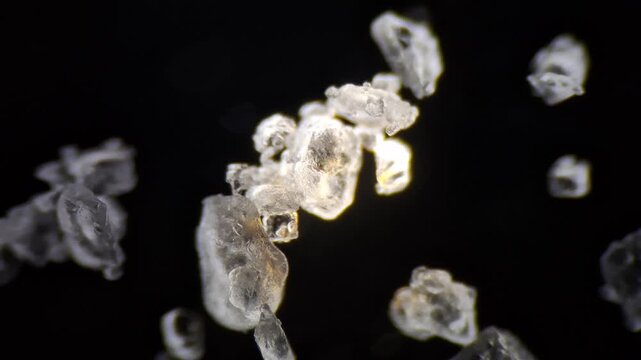 Microscopic view of table salt crystals with focus pull on black background, macro. 