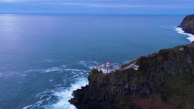 Historic Farol Do Arnel Lighthouse On A Volcanic Cliff And The Seascape In The Azores, Portugal. - aerial shot
