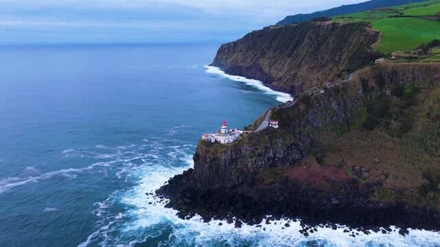Ponta Do Arnel Lighthouse With Waves Crashing On Rocky Coastline At Sunrise In Sao Miguel, Azores, Portugal. - aerial shot