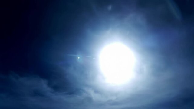 Low angle timelapse sun on blue sky concept. Bright sun shining in a cloudy blue sky during daytime with soft light and atmospheric clouds