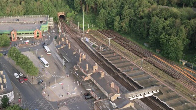 Aerial view of busy railway platforms, tracks, and station entrance with people and buses