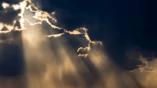 Dramatic sunlight rays breaking through dark storm clouds creating a mystical sky scene