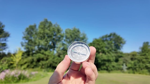 Hand Holding Compass in Sunny Green Park
