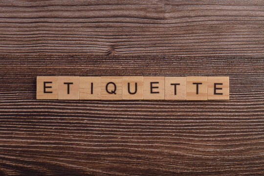 Wooden letter blocks spelling ETIQUETTE on a wooden background, representing professional behavior, good manners, social skills, workplace ethics, respect, and communication.