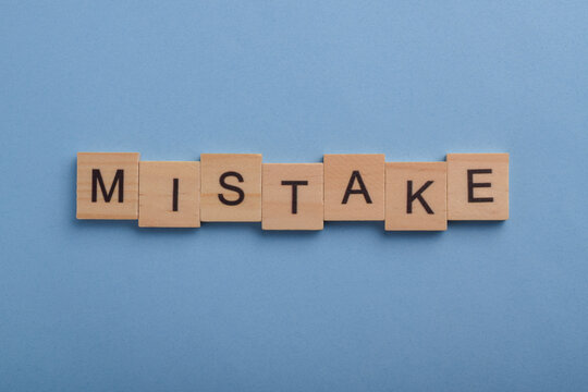 Wooden letter tiles spelling mistake on a blue background, symbolizing errors, learning, correction, problem solving, improvement, and personal development concepts.