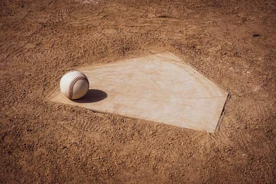 Baseball sitting on home plate of sports field