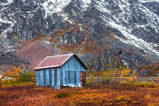 Alaskan shack standing in autumn tundra with mountains
