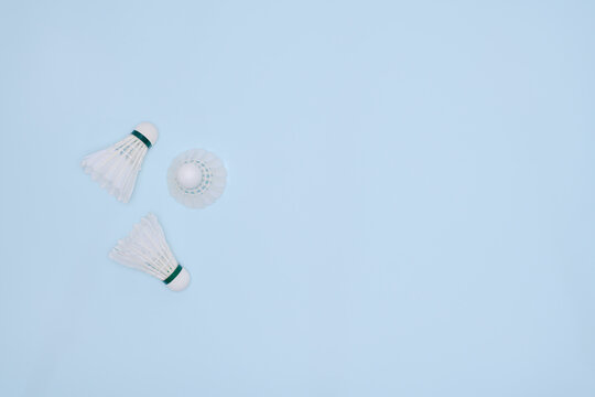 Three Badminton Shuttlecocks Arranged on a Pastel Blue Background