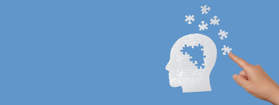 A hand points at puzzle pieces being added to a brain illustration