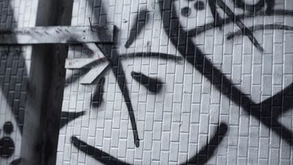 Monochromatic graffiti line art painted on a white tiled urban street wall with selective focus texture. © Vitchapon