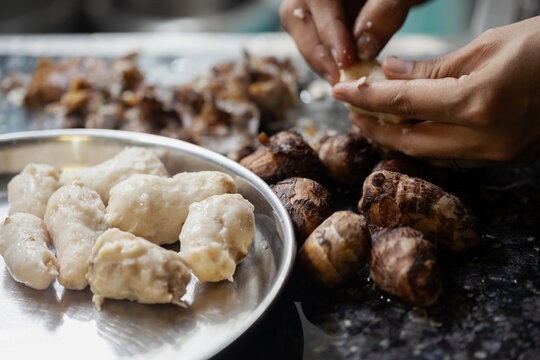 Indian female hands peeling boiled taro root for cooking