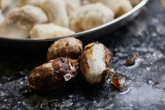 Boiled taro root peels beside peeled arbi during food preparation
