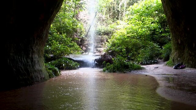 A cinematic view of a hidden waterfall inside the Maroaga Cave, surrounded by lush green jungle. Capturing the essence of ecofriendly travel and sustainability in the Amazon.