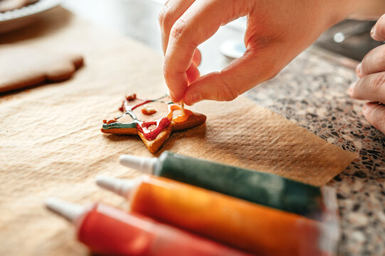 Close up of hand decorating Christmas tree cookie with icing sprinkles
