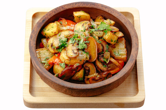 Roasted potatoes with mushrooms in a rustic clay bowl