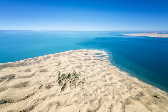 Aerial view of Golden Bay at Qinghai Lake, China, showcasing expansive sand dunes meeting turquoise waters under a clear blue sky