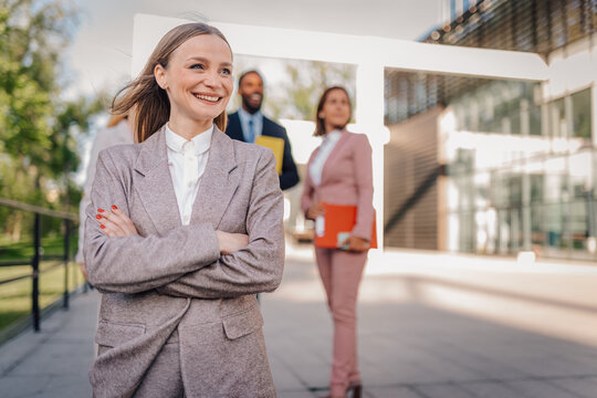 Confident businesswoman smiling with business team outdoors