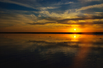 Fototapeta premium Wide Panoramic Golden Sunset Sky Reflection on Calm Lake Water Horizon Dramatic Cloud Evening