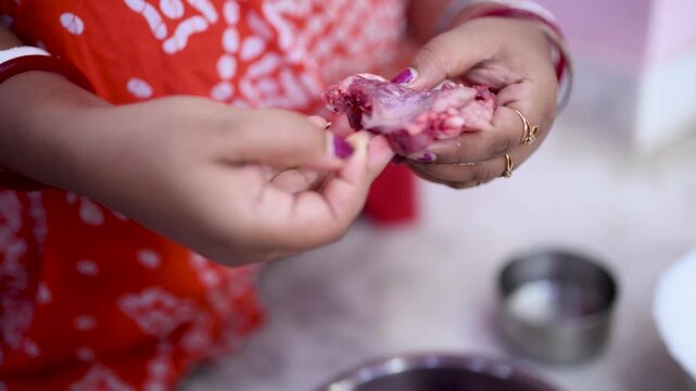 A married Indian woman (only hand showing) hygienically cleans fresh red mutton pieces by hand in a clean kitchen, emphasizing food safety, cleanliness, traditional cooking, careful meat preparation.