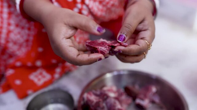 A married Indian woman hygienically cleans fresh red mutton pieces by hand in a clean kitchen, emphasizing food safety, cleanliness, traditional cooking, and careful meat preparation