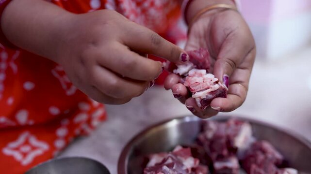 A married Indian woman (only hand showing) hygienically cleans fresh red mutton pieces by hand in a clean kitchen, emphasizing food safety, cleanliness, traditional cooking, careful meat preparation.
