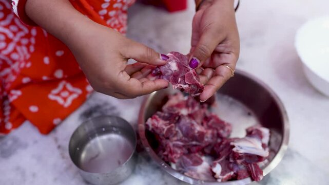 A married Indian woman hygienically cleans fresh red mutton pieces by hand in a clean kitchen, emphasizing food safety, cleanliness, traditional cooking, and careful meat preparation