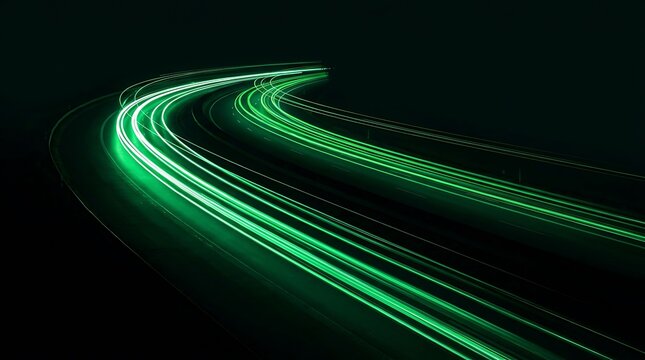 Green light trails from fast moving cars on a highway curve at night with long exposure effect