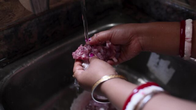 An Indian married woman hygienically washing fresh raw mutton in a kitchen basin before cooking. Close-up of clean red meat preparation, traditional home cooking, food safety, healthy meal preparation