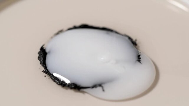 Cracked raw egg with dark shell on white plate