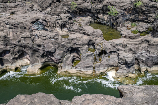 A high-angle shot of the naturally formed basalt rock potholes, locally known as Ranjan Khalge, carved over centuries by the Kukadi River in Nighoj, Ahmednagar district, Maharashtra, India.